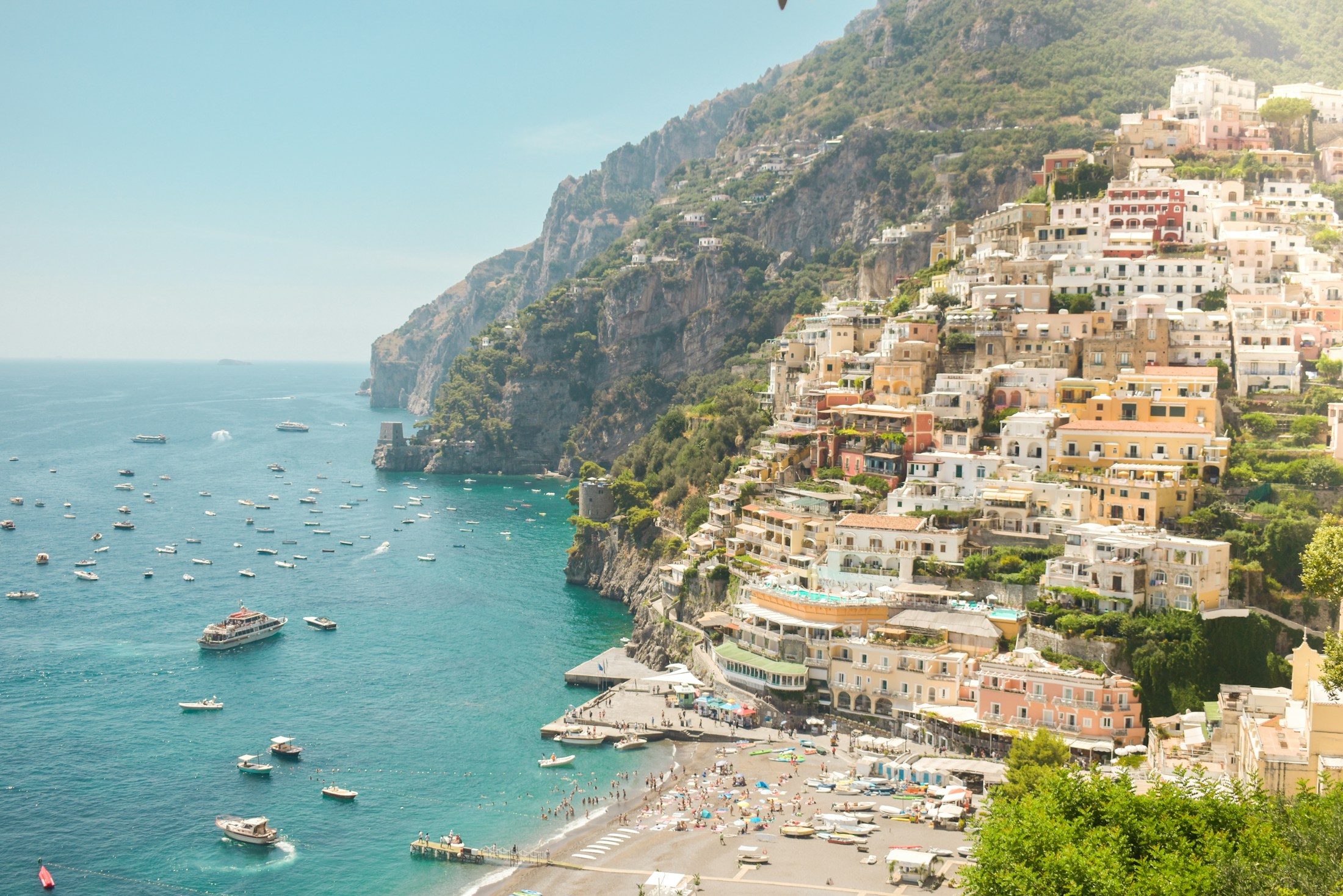 Sunlit Positano overlooking the Mediterranean, with boats along the coast
